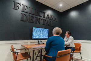 Dr. JACOB R. DIEBOLD,DDS explaining xrays to older female patient in feliciana dental patient room
